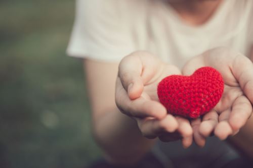 Child holding a red crocheted heart.