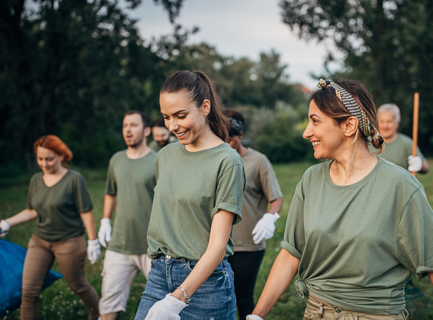 Team of volunteers, wearing white work gloves, walking across a field.