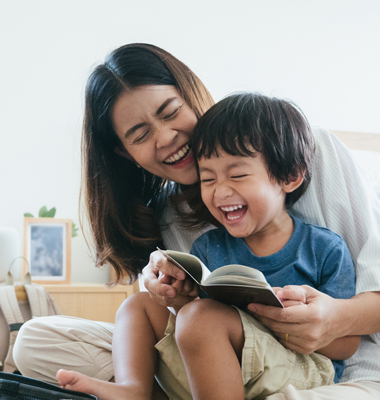 Mother and young son laughing while packing for trip.