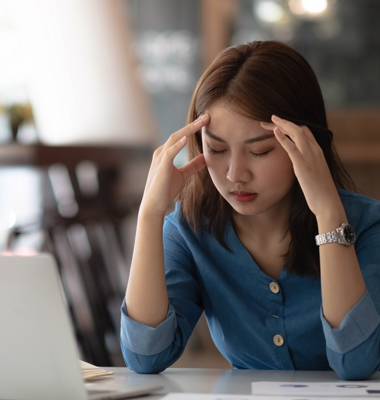 Woman on laptop stressed about budgeting.