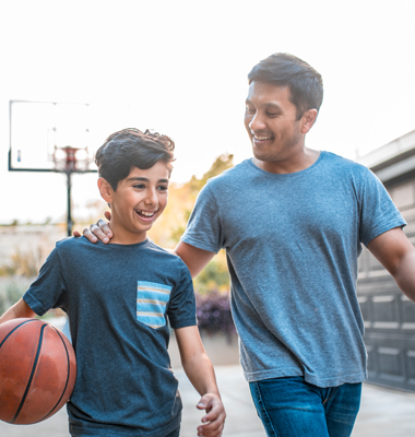 Father and son walking back home after playing basketball.