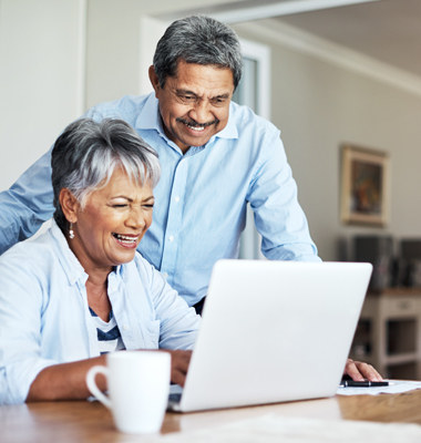 Middle-age couple reviewing savings plan on laptop.