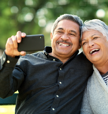 Mature couple on park bench taking selfie.