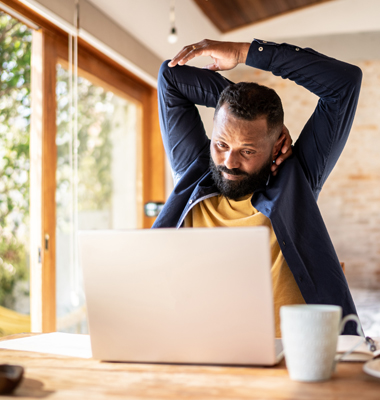 Man doing arm stretching exercise in front of laptop.