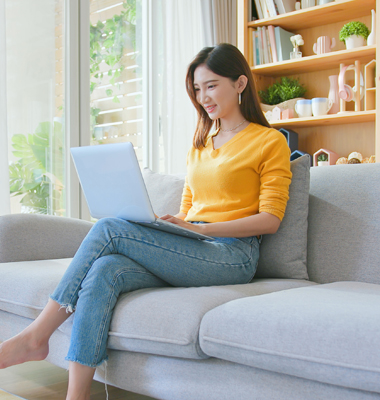 Young woman sitting on living room couch using laptop.
