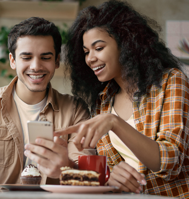 Young couple in coffee shop using mobile banking app.