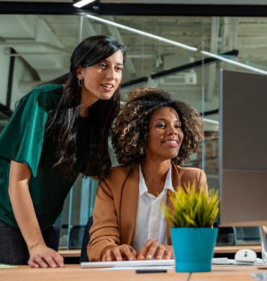 Two businesswomen working at desktop computer in high-tech office.