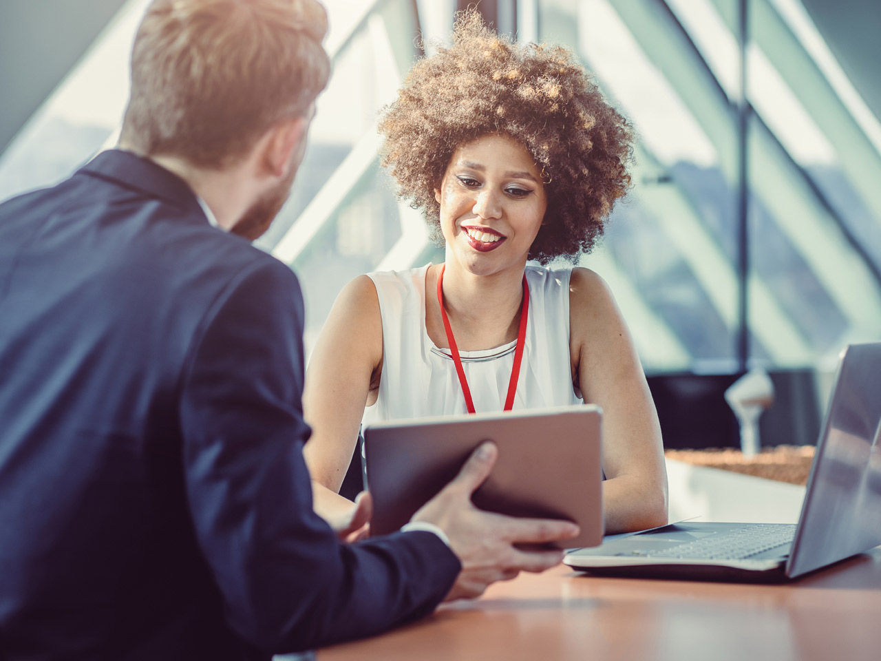 Coworkers in modern office going over data on a smart tablet.