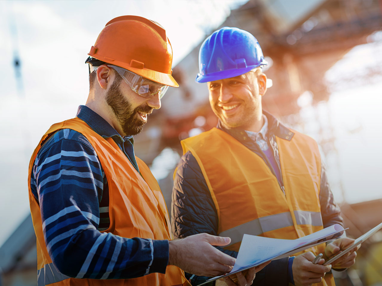Two men in hard hats discussing loans at construction site.
