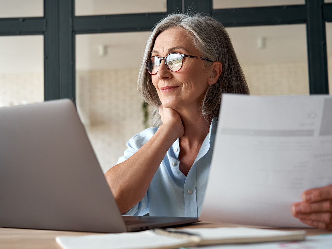 Mature woman reviewing retirement plans on laptop.