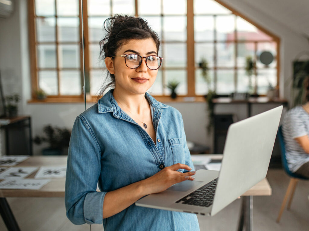 Young female designer working on laptop in creative studio.