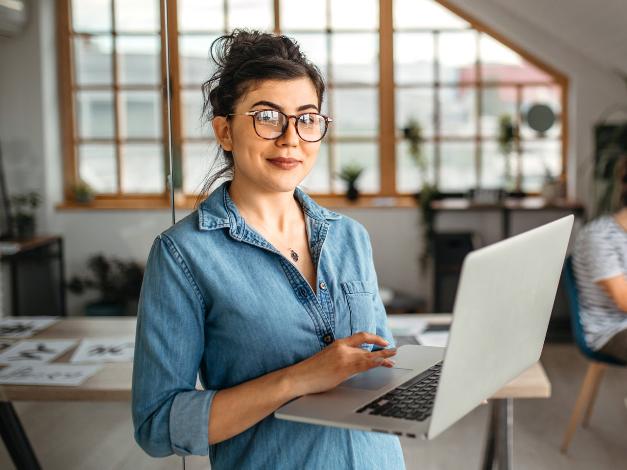 Young female designer working on laptop in creative studio.