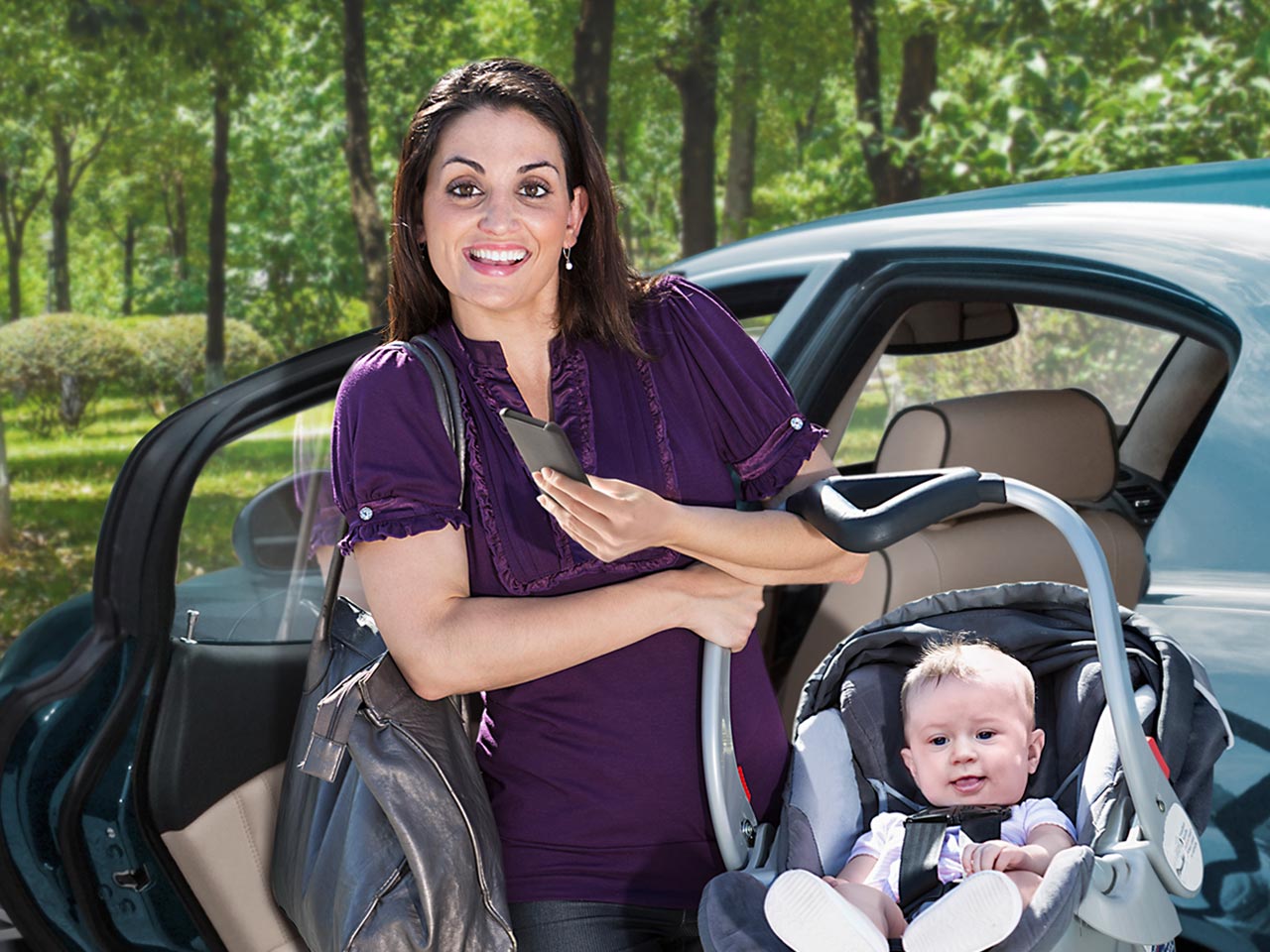 Busy mom with happy baby in carrier, holding her purse an smartphone.