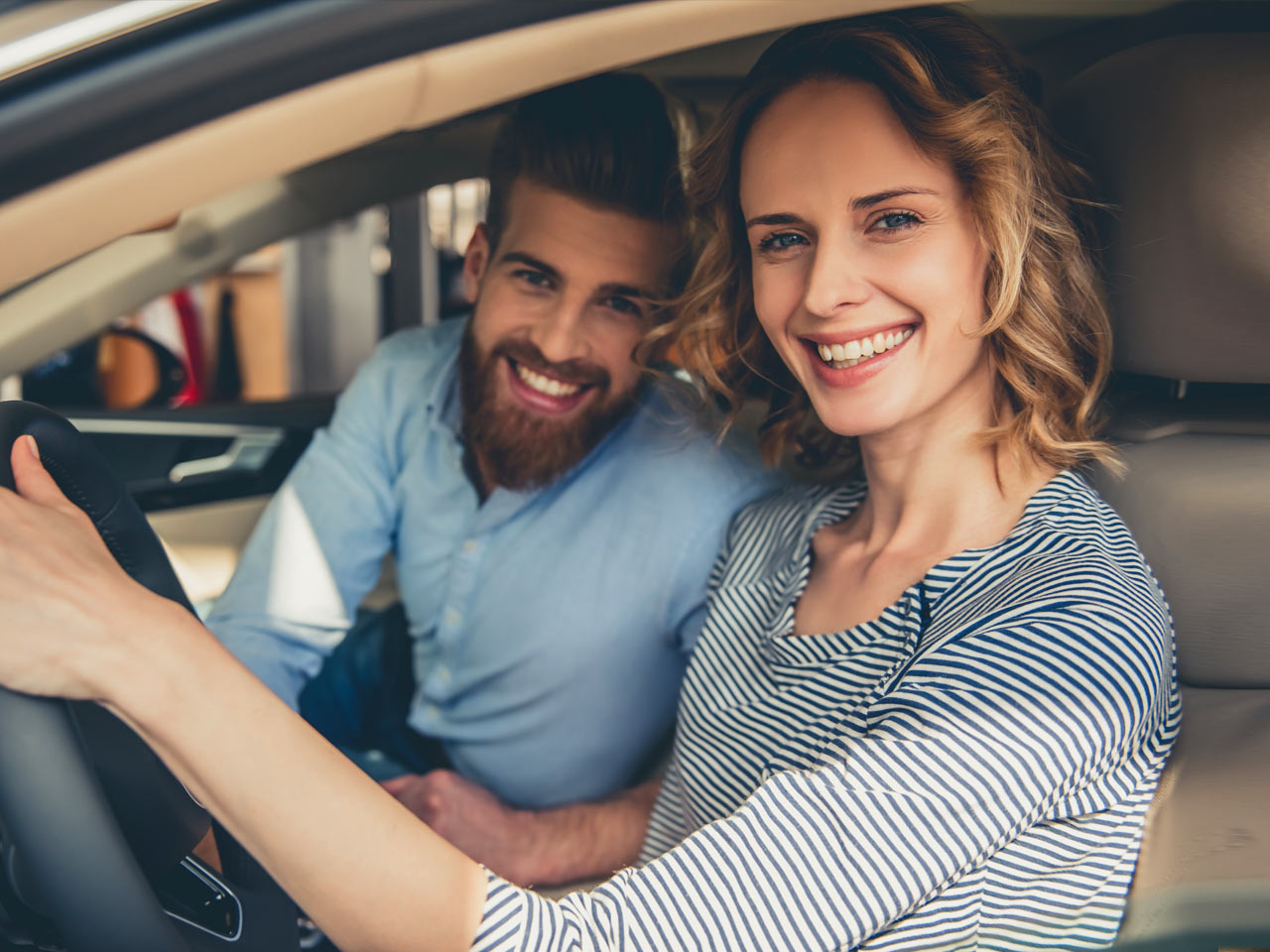 Attractive young couple sitting in front seat of new car