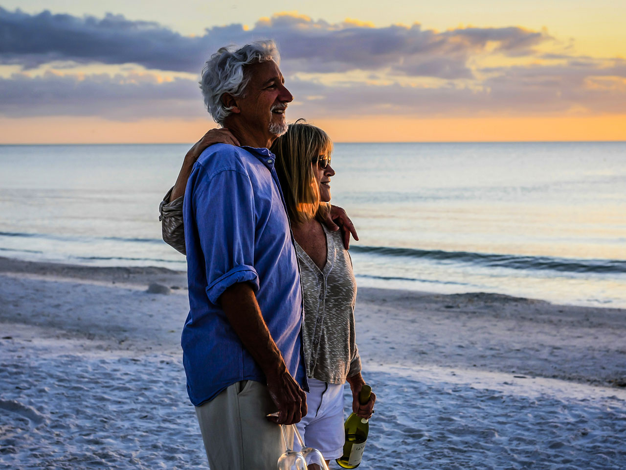 Middle-aged couple standing on the beach at sunset.