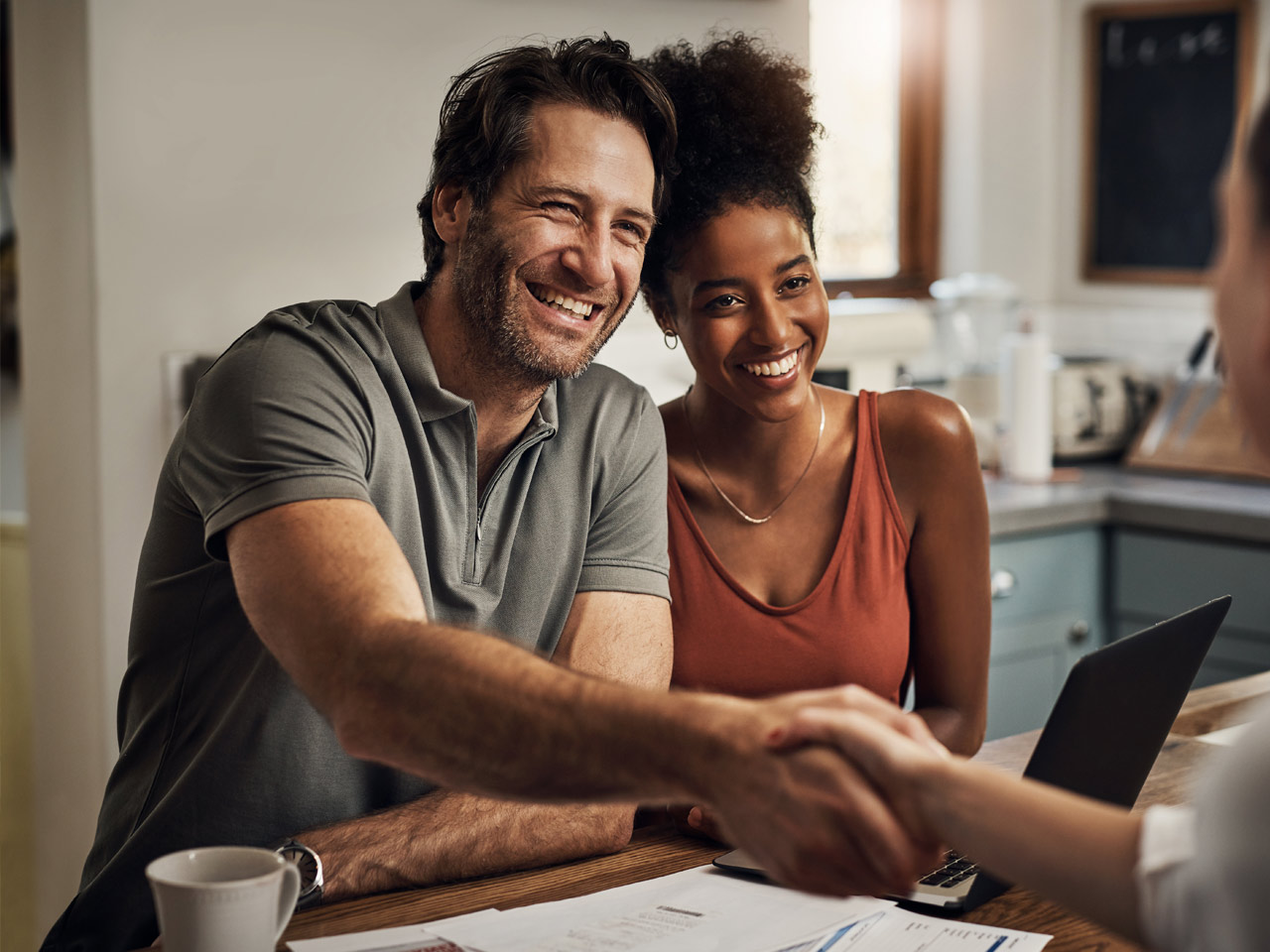 Couple shaking hands with insurance agent in office.