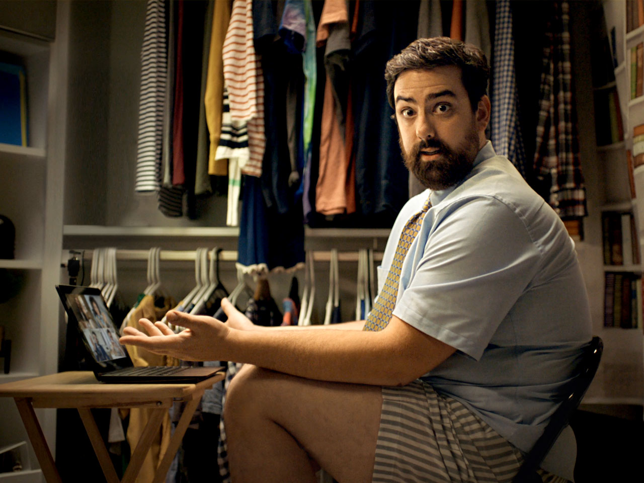 Man sitting in cramped closet office attending online meeting.