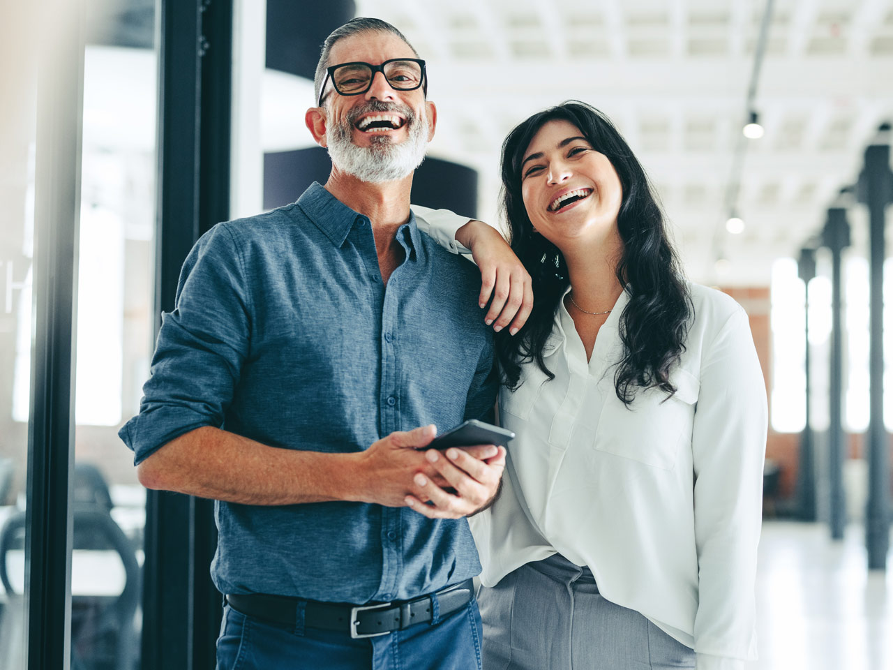 Office colleagues laughing in hallway.
