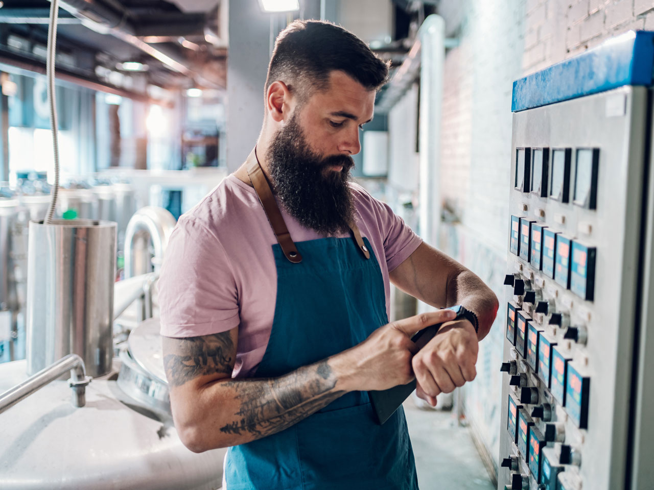 Male factory worker checking bank info on smartwatch.