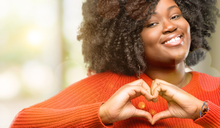 Smiling female employee employee making heart shape with hands.