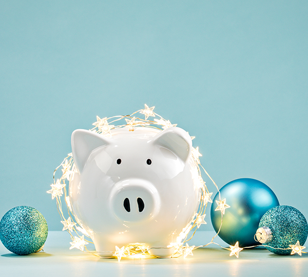 Piggy bank wrapped in a string of Christmas lights