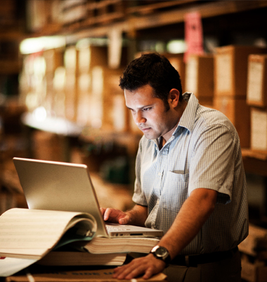 Man entering numbers on laptop in warehouse.
