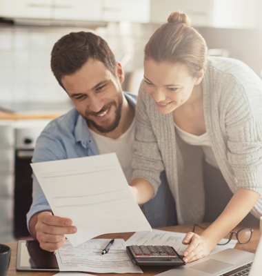Happy young couple paying bills at kitchen table