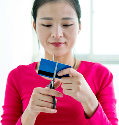 Young woman cutting credit card with scissors
