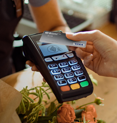 Contactless 1st Source Bank VISA credit card being used with card reader at floral shop.