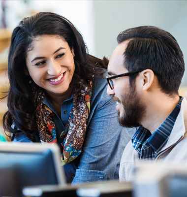 Female coworker consulting with male worker at computer.