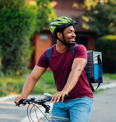 Man on bicycle with backpack, delivering food order.