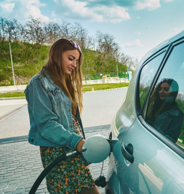 Young woman filling gas tank at gas station.