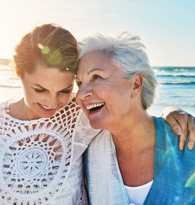Mature daughter with elderly mother on a sunny day at the beach.