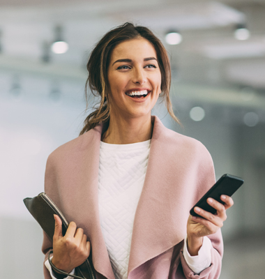 Young female business owner standing in underground parking lot and holding smartphone