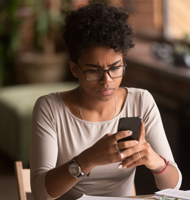 Young woman viewing smartphone screen with a puzzled look.