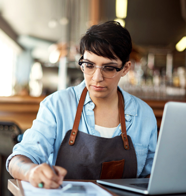 Young female restaurateur taking notes for website.