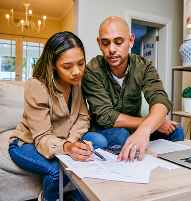 Young couple sitting at living room table reviewing loan options.