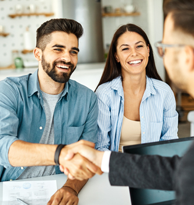 Small business owners shaking hands while manager looks on.