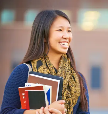 Optimistic female college student holding books.