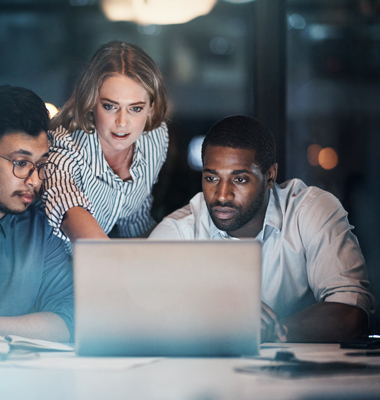 Three young business owners reviewing financial data on a laptop.
