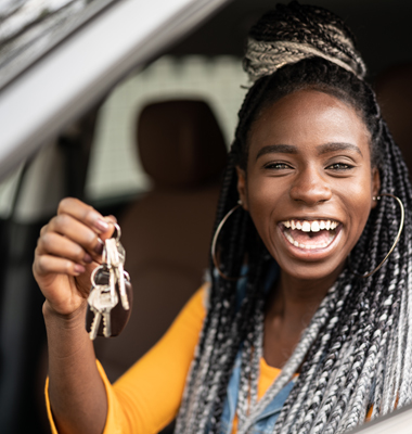 Happy young lady holding up keys in new car.