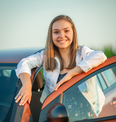 Young lady leaning on car door.