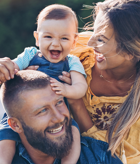 Youthful other and father playing with happy baby outdoors.