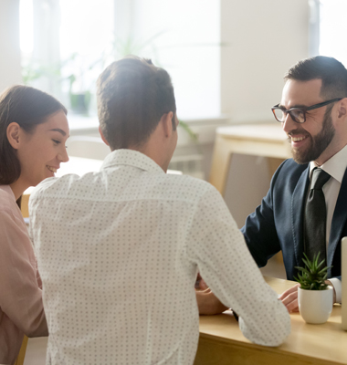Young couple working with banker in brightly lit office.