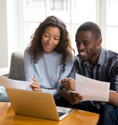 Couple reviewing financing options on a laptop at living room table.