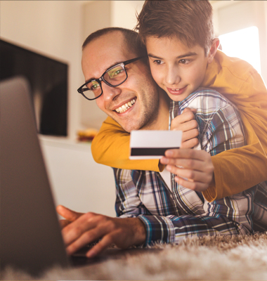 Father and young son holding credit card looking at laptop.