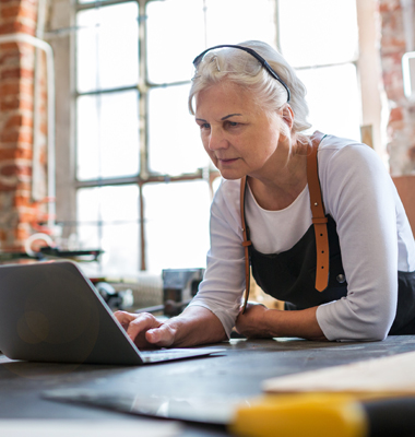 Mature woman in workshop using laptop.