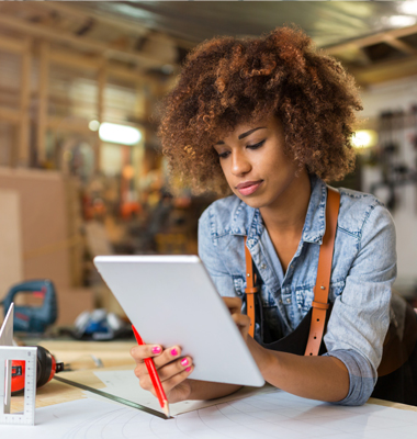 Young wood shop owner performing a calculation on her smart tablet.