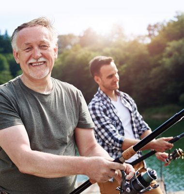 Older father with grown son out fishing on the lake.