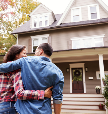 Couple standing out in yard, looking at house.